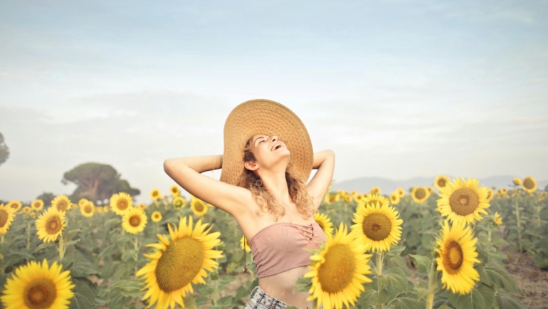 Managing Fibromyalgia Flareups feels like this woman enjoying the sunshine while standing in sunflower field.